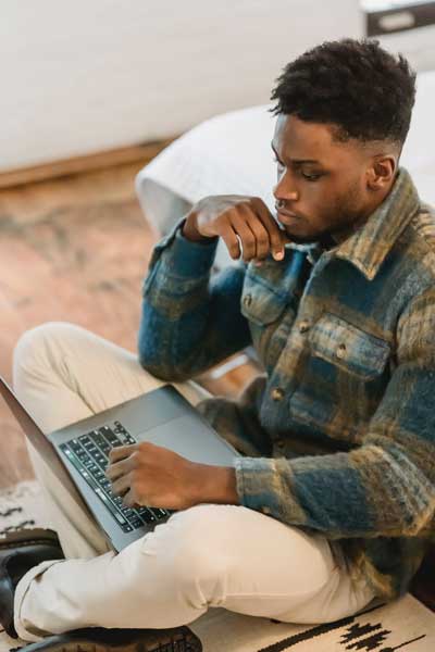 a person sitting on the floor looking at a laptop